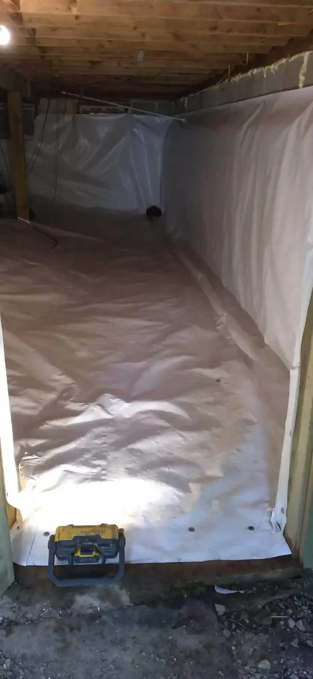 Crawl space lined with a white vapor barrier